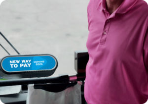 Person standing next to validator machine on bus that says New Way to Pay